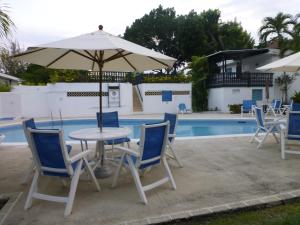 uma mesa e cadeiras com um guarda-sol ao lado de uma piscina em Rockley Golf Club, 2 bed 2 bath Pool, Tennis, Golf, Bar & Restaurant! em Bridgetown