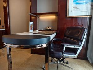 a desk and a chair in a room with a desk at Sheraton Grand Zhengzhou Hotel in Zhengzhou