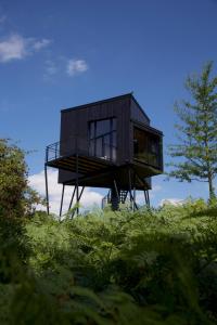 a black house sitting on top of a hill at Treeangle - K1 Baumhaus in Odenthal