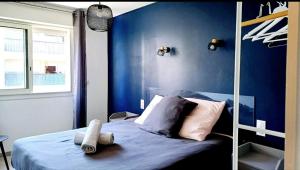 a bedroom with a bed with a blue wall at Spacieux T3 Sète, parking, 10 min à pied gare et centre ville, wifi, clim in Sète