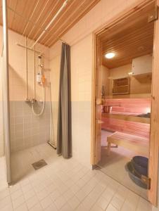 a bathroom with a shower stall and a bed at Föri condo, sauna and parking in Turku