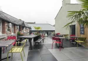 eine Terrasse mit bunten Stühlen und Tischen sowie einem Tisch und Stühlen in der Unterkunft The Queen's Head Wetherspoon in Tavistock