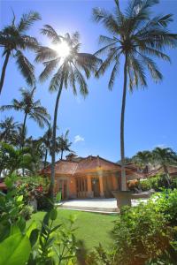 a house with two palm trees in front of it at Villa Rama in Candidasa
