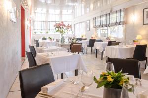 un restaurante con mesas blancas, sillas y flores en Logis Le Pont Bernet, en Le Pian-Médoc