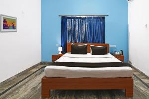 a bedroom with a large bed with a blue wall at Hotel O Home Elite Stay Near Shri Shri Shiridi Sai Mandir in Bhubaneshwar +22 photos