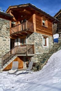 two chairs in the snow in front of a log cabin at MCX Vacation Rental - MAISON LOZ Duplex in villaggio tipico Valdostano con comfort moderni e panorama mozzafiato in Valtournenche