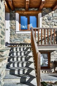 a stone house with wooden stairs and a window at MCX Vacation Rental - MAISON LOZ duplex in typical village in Valtournenche with modern comforts just 2 minutes from the cable cars! in Valtournenche
