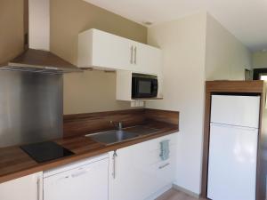a kitchen with white cabinets and a sink and a microwave at Village de Gîtes Nature et Jardin in Bouère