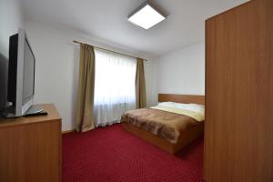 Un dormitorio con una cama y un televisor y una ventana. en Marcos Studio Apartment, en Bucarest