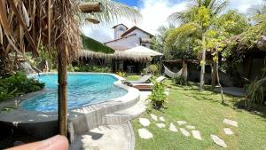 a swimming pool in a yard next to a house at Pousada Tatuamar Café & Bistrô - 150 m da praia in Pôrto de Pedras