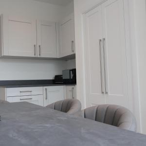 a kitchen with white cabinets and a table and chairs at Alban Suites in St. Albans +16 photos