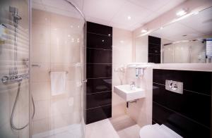 a bathroom with a shower, sink, and toilet at Arche Hotel Puławska Residence in Warsaw