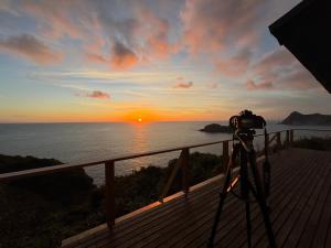 a camera on a deck with the sunset in the background at IZU Elysian View in Koura