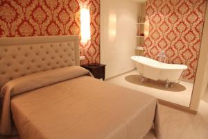 a bedroom with a tub and a bed and a sink at Hotel Restaurante Paneque in Villanueva del Trabuco