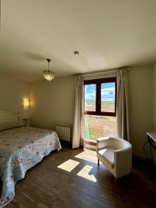 a bedroom with a bed and a chair and a window at Hotel Restaurante Paneque in Villanueva del Trabuco