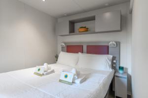 a bedroom with a white bed with two boxes on it at Club del Sole Rivaverde Easy Camping Village in Marina di Ravenna +94 photos