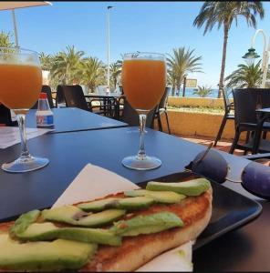 einen Tisch mit einem Sandwich und zwei Gläsern Getränken in der Unterkunft Costa Blanca Beach Apartment in Arenales del Sol