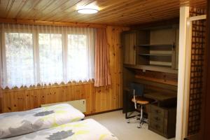 a bedroom with a bed and a desk and a computer at Saastal Apartments Haus Antrona in Saas-Almagell