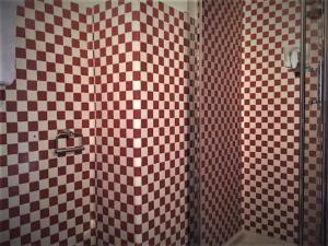 uma casa de banho com um chuveiro com azulejos xadrez vermelhos e brancos em Casa Milano - Apartments and Rooms - Duomo's Whisper em Milão