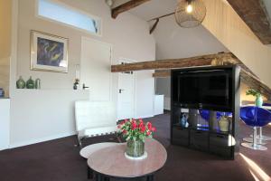 a living room with a tv and a table at Huize de Lekpoort - The Stork Loft - Loft Apartment in Vianen Center in Vianen