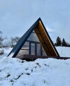 een klein huisje in de sneeuw met een dak bij Holiday Cabins in Hosasău