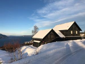 a wooden barn with snow on the ground at Villa Fjara sleeps 22 in 6 bedrooms in Ulven