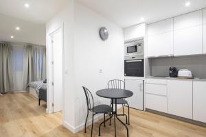 a kitchen with white cabinets and a table and chairs at Garo in Vigo +2 photos