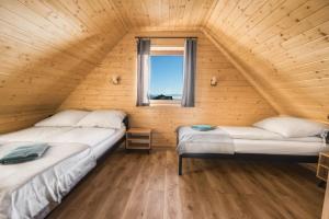 Habitación de madera con 2 camas y ventana en Domek pod Herbikiem, en Odrowąż
