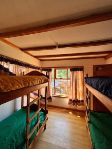 a room with three bunk beds and a window at Jardín de Rosas Hostel in El Bolsón