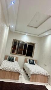 a bedroom with two beds and a window at Très belle appartement à louer sur bouznika de 117 m2 avec ascenseur in Bouznika