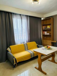 セレスにあるDowntown Comfy Studio 31のリビングルームに置かれた黄色いソファとテーブル