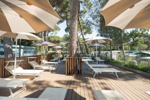 a deck with tables and chairs and umbrellas at Club del Sole Rivaverde Easy Camping Village in Marina di Ravenna