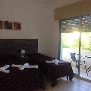 a bedroom with two beds and a table and a patio at Hotel Palace Piriápolis in Piriápolis