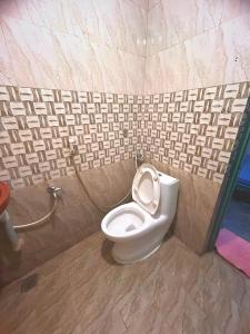 a bathroom with a toilet in a tiled wall at AURO GUEST HOUSE in Auroville