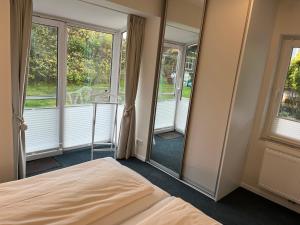 a bedroom with a bed and two windows at Sander's Höft Appartments - Direkt am Strandaufgang in Juist