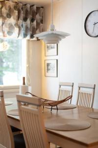 une salle à manger avec une table, des chaises et une horloge dans l'établissement Villa Arctic Harmony near SCV, à Rovaniemi