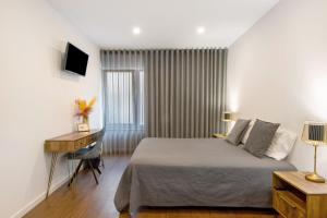 ein Schlafzimmer mit einem Bett, einem Schreibtisch und einem Computer in der Unterkunft Jm Stay Aveiro in Aveiro