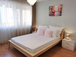 a bedroom with a bed with white sheets and pink pillows at Deak Ferenc ter Central Apartment in Budapest