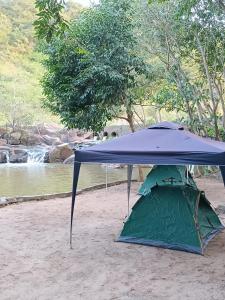 a blue tent sitting in the sand next to a river at Balneário Rio Agua Viva - Área de Camping in Areia