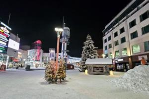 a city at night with a christmas tree and buildings at Charming 1BR Suite with Sauna Fast Wi-Fi Downtown in Rovaniemi