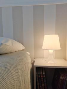 a white lamp on a night stand next to a bed at L' Orso Felice - alloggio turistico a Campo Felice in Collimento