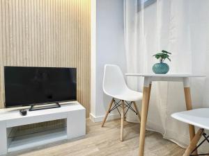 un soggiorno con TV e tavolo con una pianta di Minimalist Studio with Mezzanine a Lisbona