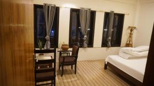 a bedroom with a bed and a chair and windows at Kathmandu home in Kathmandu