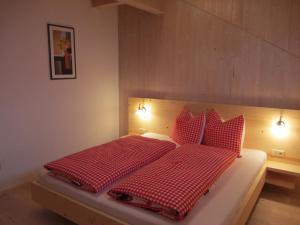 a bedroom with a red and white bed with red pillows at Liebharterhof in Valdaora