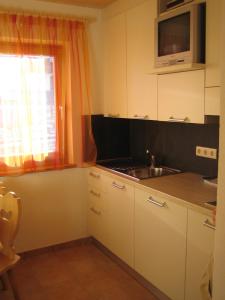 eine Küche mit weißen Schränken, einem Waschbecken und einem Fenster in der Unterkunft Liebharterhof in Olang