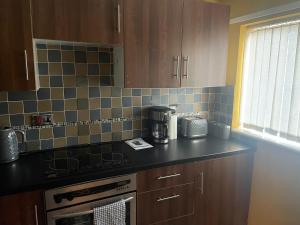 cocina con armarios marrones y encimera negra en Tipton 2 Bedroomed long Stay Pad van or car free parking, en Ocker Hill