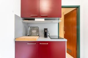 a kitchen with red cabinets and a coffee maker at Ferienwohnung Seebruck in Seebruck +14 photos