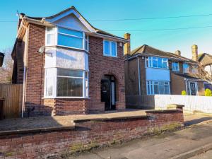 a red brick house with a white fence at Chelsea House in Melton Mowbray