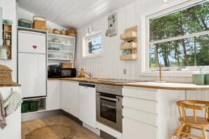 a kitchen with white cabinets and a sink and a window at Rødby, Bredfjed nær Lalandia in Rødby +10 photos