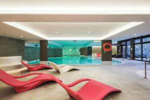 Habitación con 3 sillas rojas frente a la piscina en MERIBEL Appartement Neuf Résidence Hevana, en Méribel